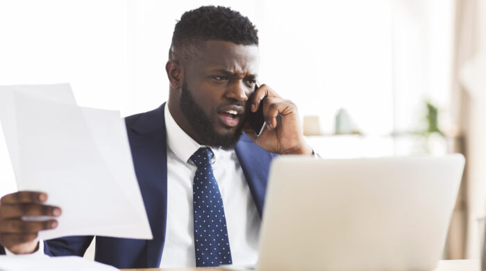 Furious african american general manager yelling at employees by phone, unhappy with business report, office interior, copy space