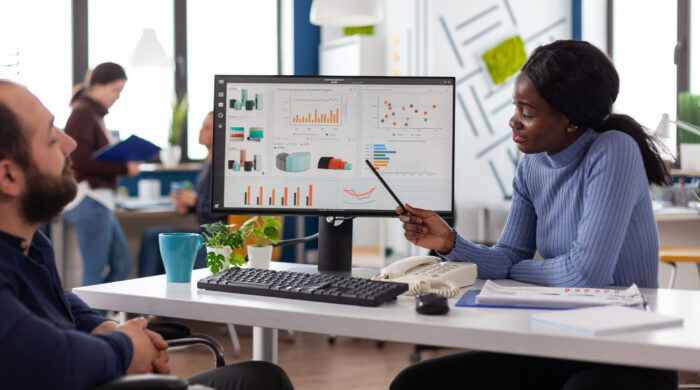 Paralyzed    businessman working at management strategy with african american collegue analyzing company graphs in startup office. Diversity team discussing business project