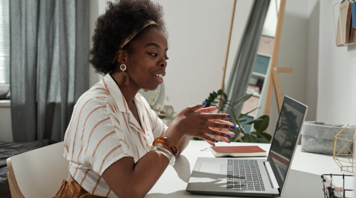 Young African female freelancer communicating in video chat in front of laptop