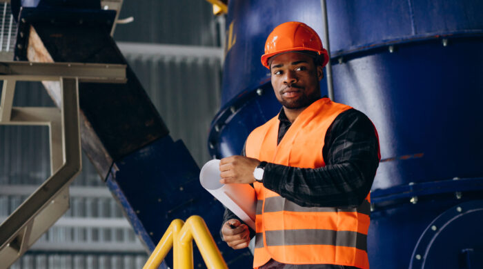 African American Worker Standing In Uniform Wearing A Safety Hat In A Factory