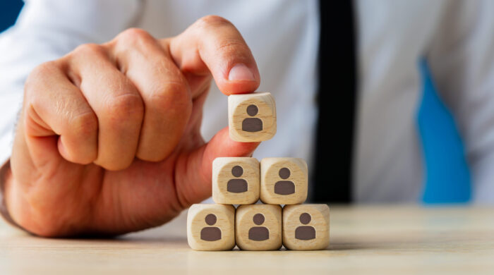 Business Executive Stacking Wooden Dices With People Icons On T