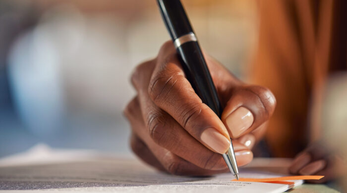 Close Up Of Black Woman Hand Writing On Business Document